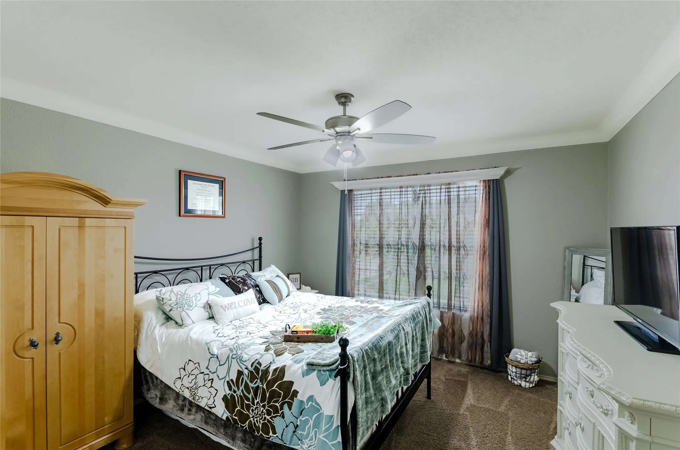 Spacious room featuring neutral wall tones, crown molding, a ceiling fan with integrated lighting, and a large window with blinds