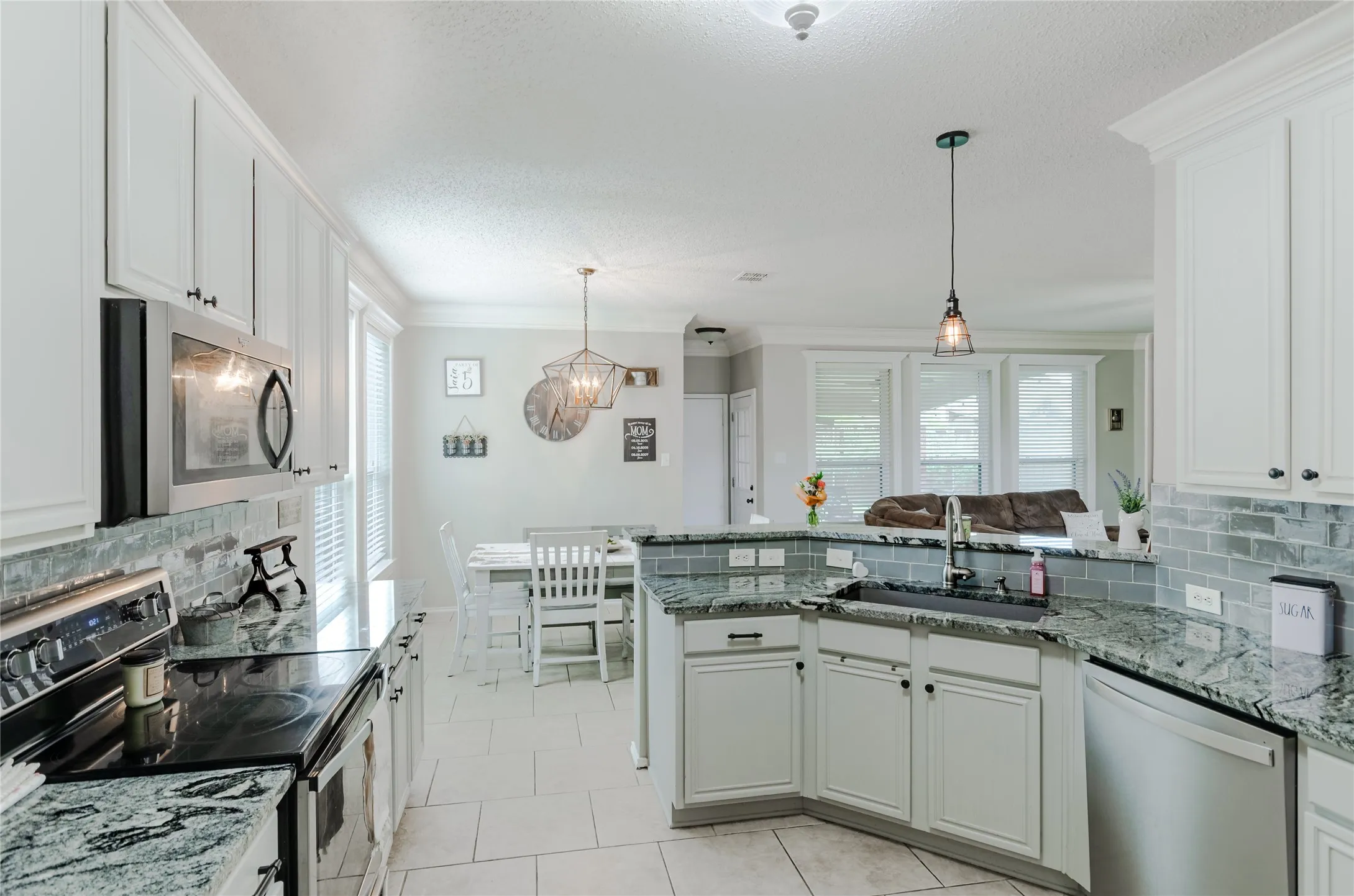 Kitchen featuring white cabinetry, stainless steel appliances, granite countertops, and a subway tile backsplash