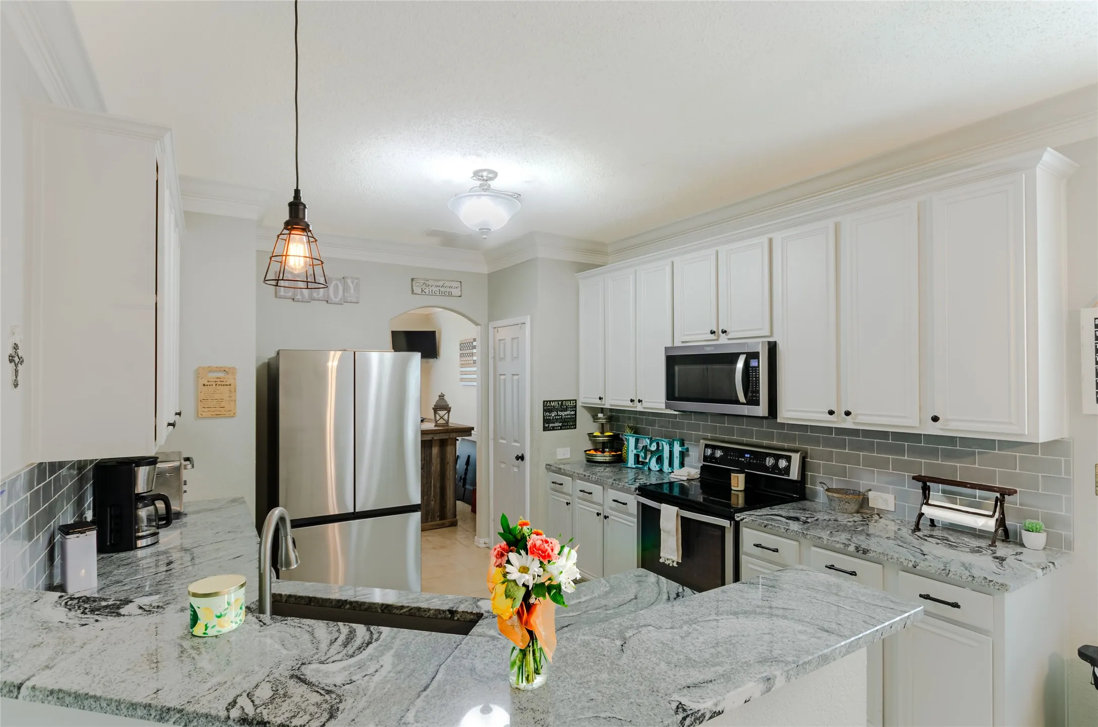 Kitchen featuring white cabinetry, stainless steel appliances, grey subway tile backsplash, and light-granite countertops