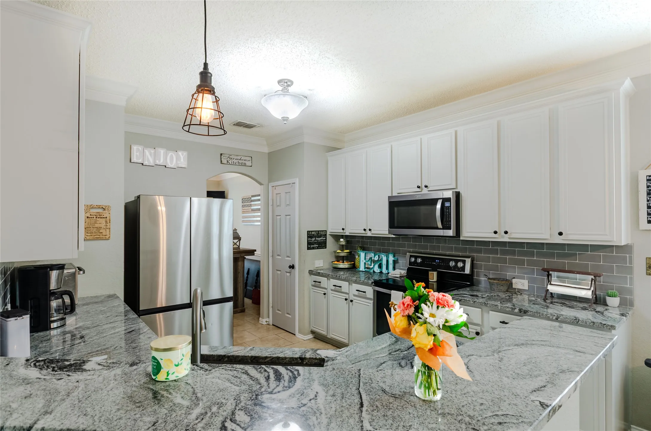 Spacious kitchen featuring white cabinetry, gray subway tile backsplash, stainless steel appliances, and granite countertops