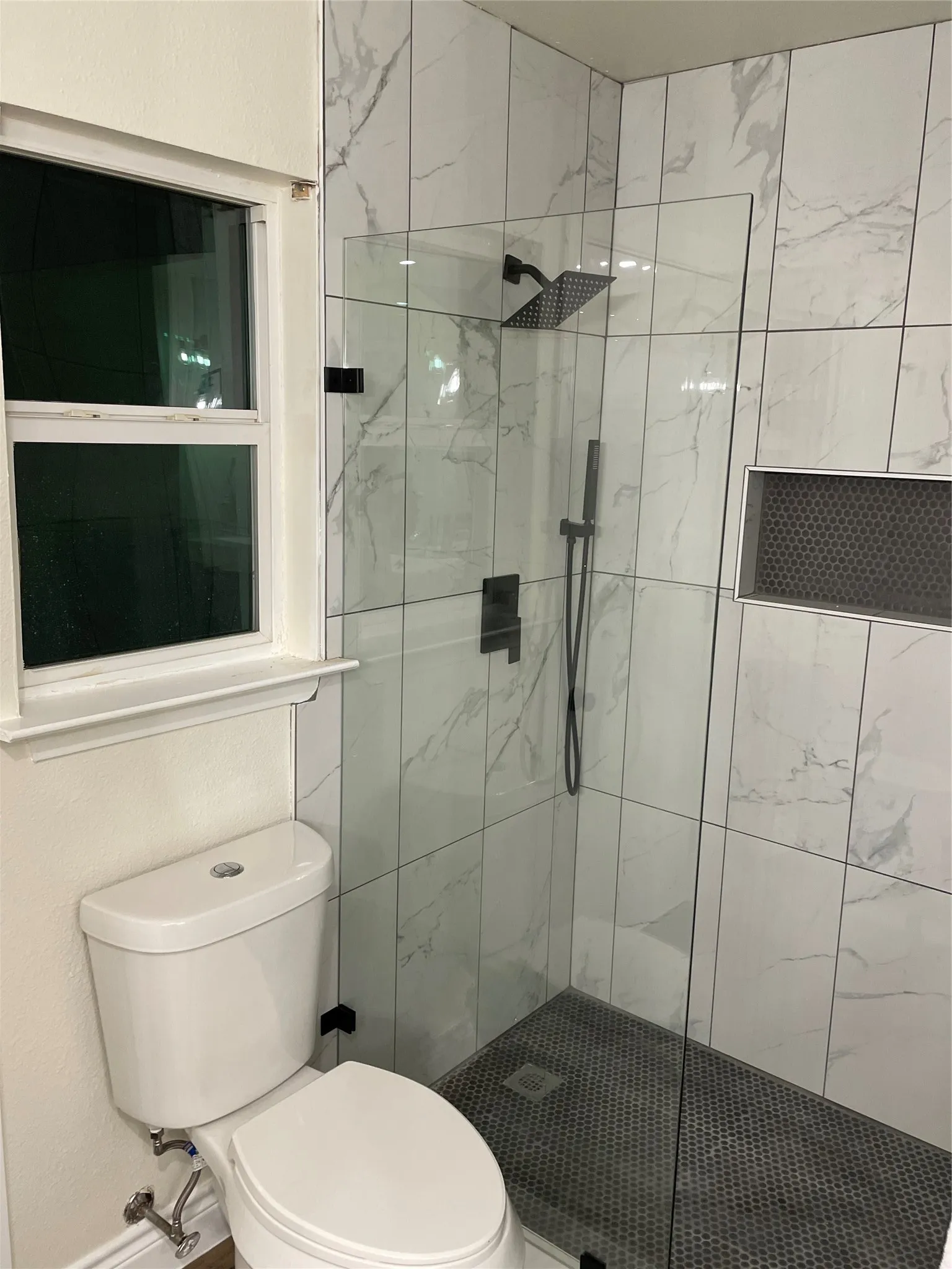 Modern shower enclosure featuring glass panels and matte black hardware