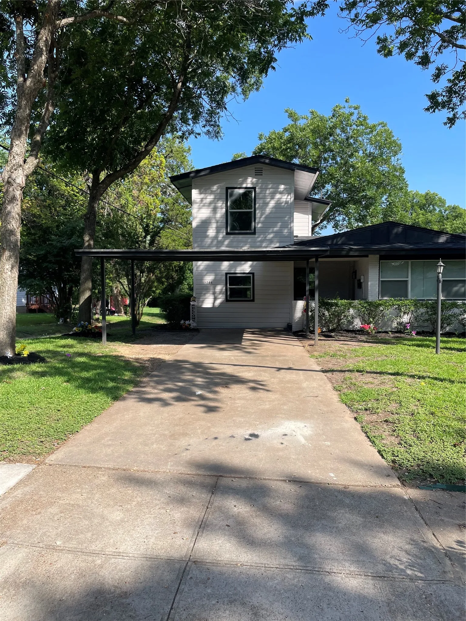 White siding exterior featuring black trim windows and a covered carport