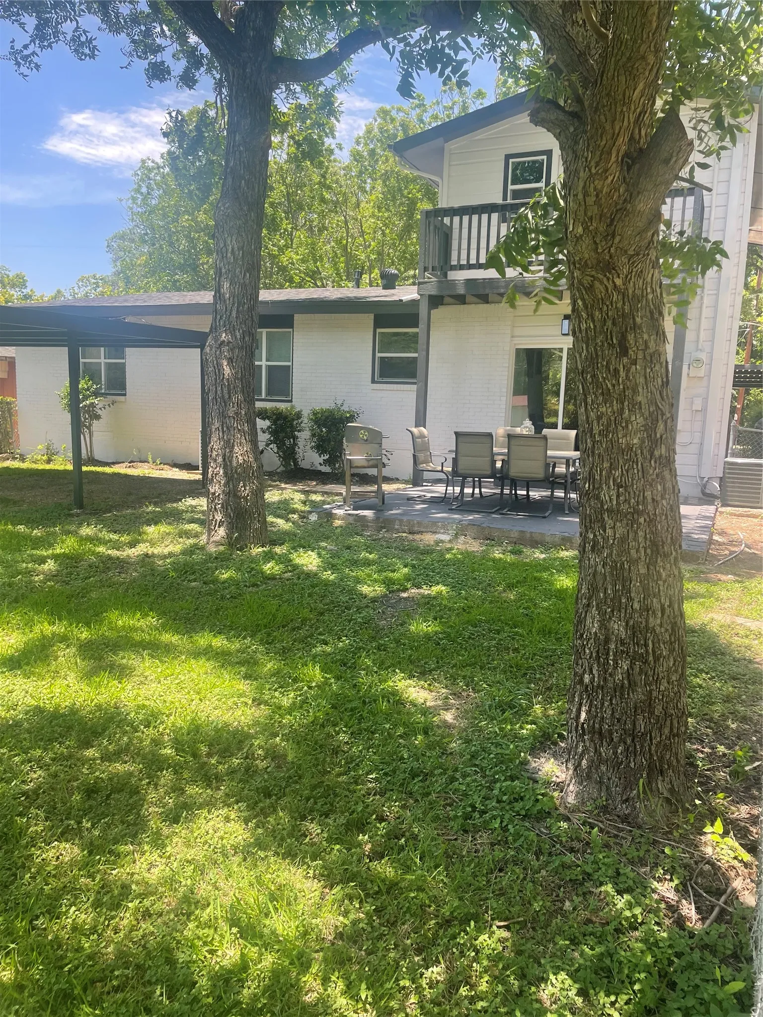 Spacious backyard with mature trees, a concrete patio, and a covered patio area