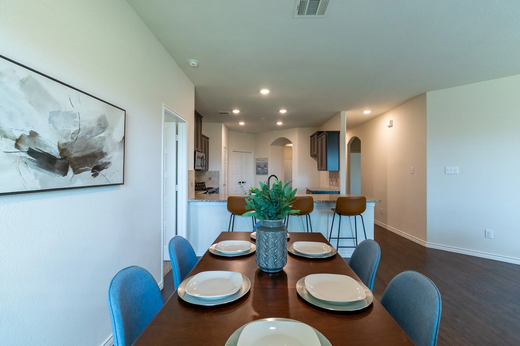 Dining area featuring wood-finish flooring and a kitchen pass-through with granite countertops and dark wood cabinetry