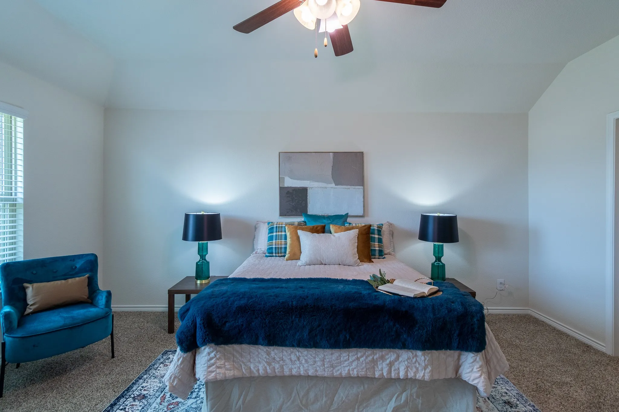 Carpeted bedroom featuring vaulted ceilings, a ceiling fan with light fixture, and a window with blinds
