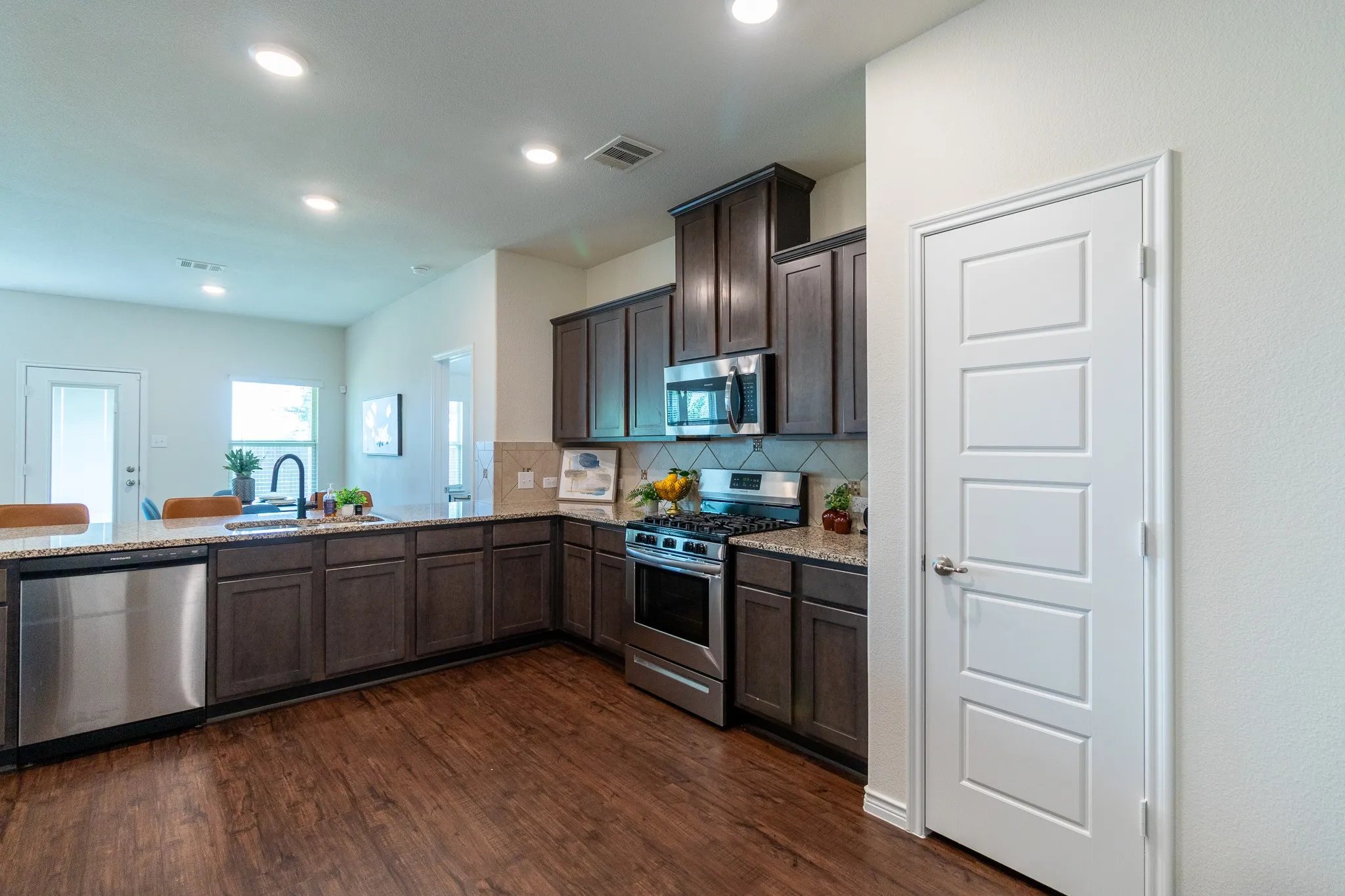 Kitchen featuring wood-finish flooring, dark wood cabinetry, stainless steel appliances, and light-toned​​‌​​​​‌​​‌‌​‌‌​​​‌‌​‌​‌​‌​​​‌​​ countertops