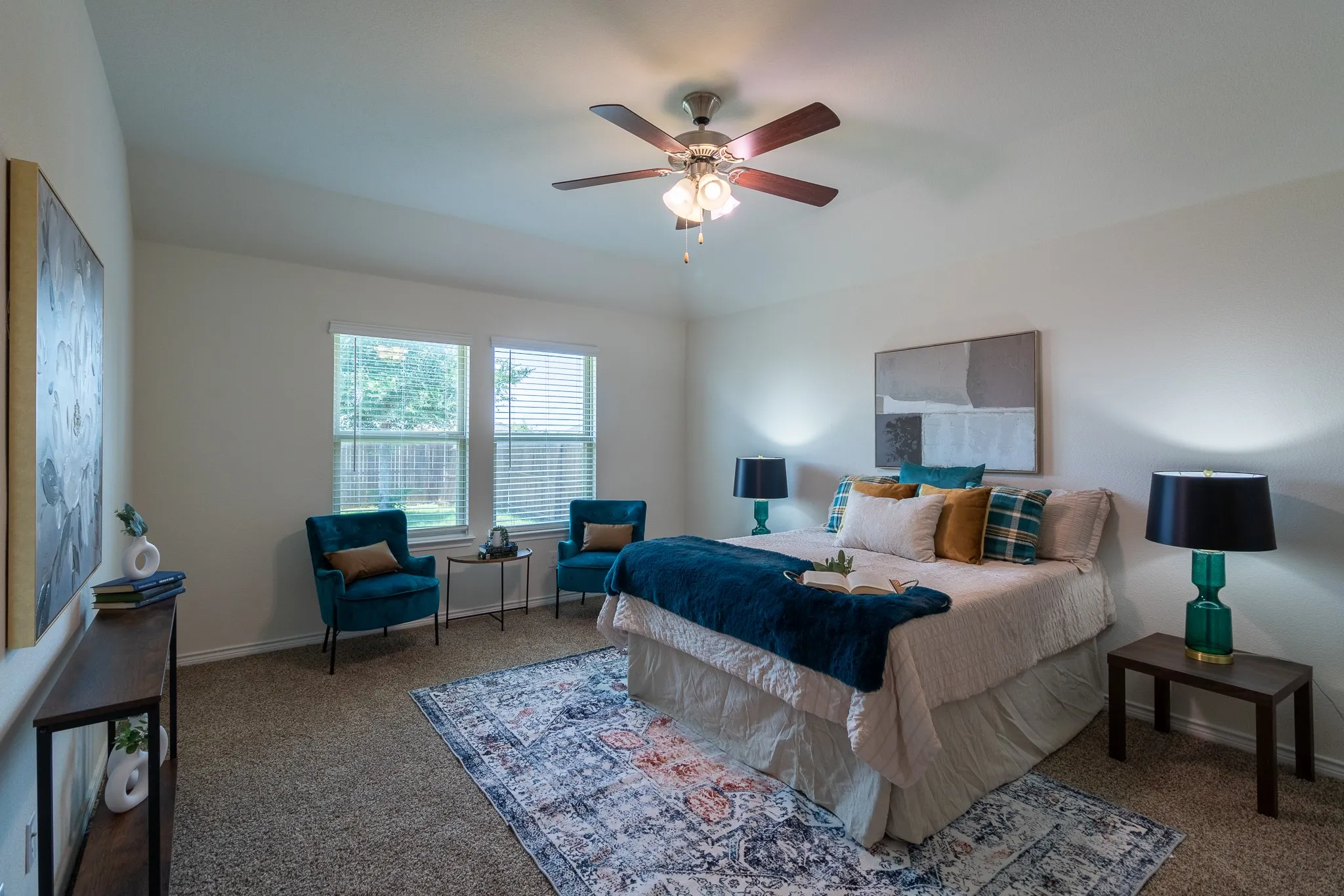 Carpeted bedroom featuring two large windows with blinds, a ceiling fan with integrated lighting, and vaulted ceilings