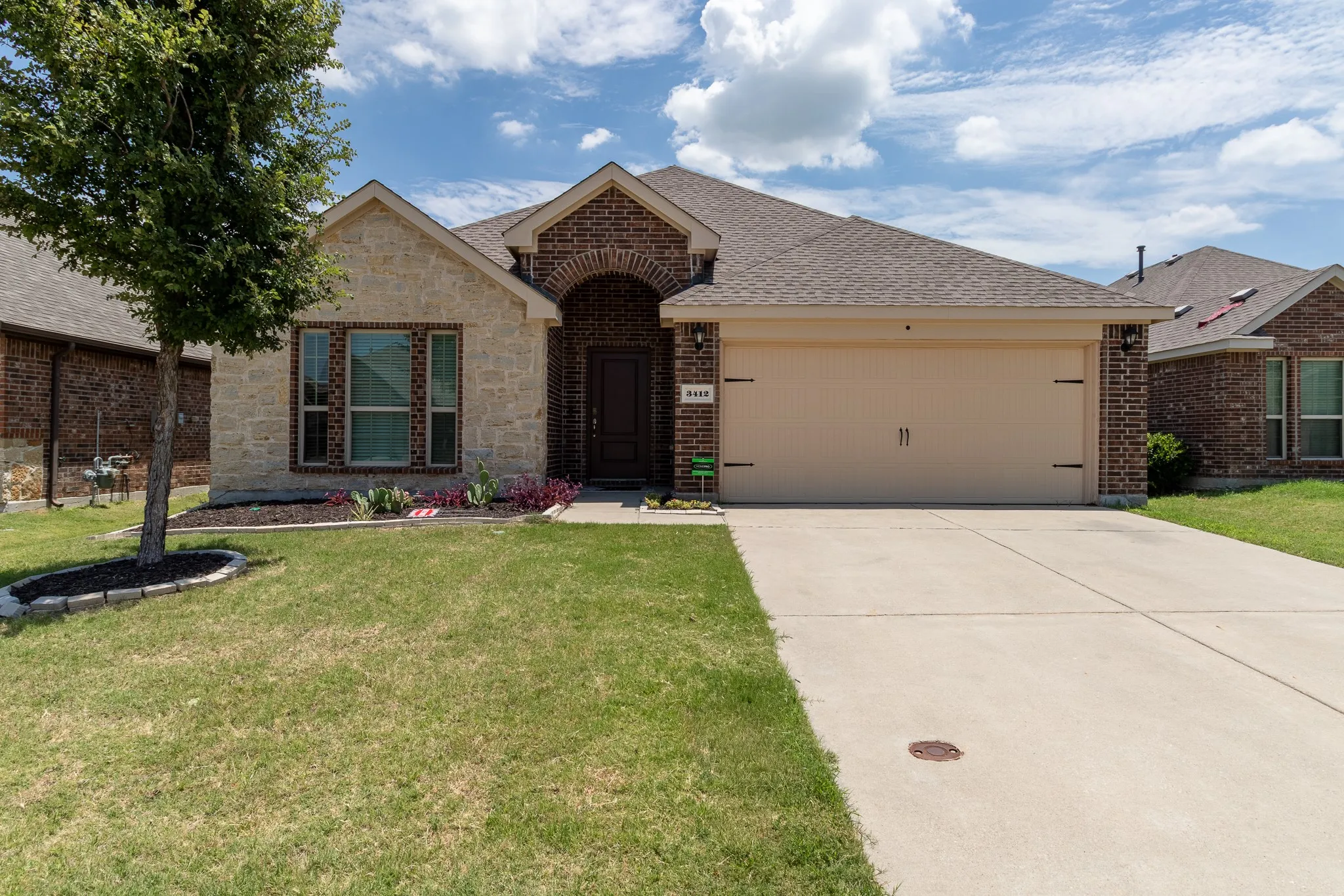 Single-story residence featuring a brick and stone facade, an arched entry, a two-car garage, and a concrete driveway