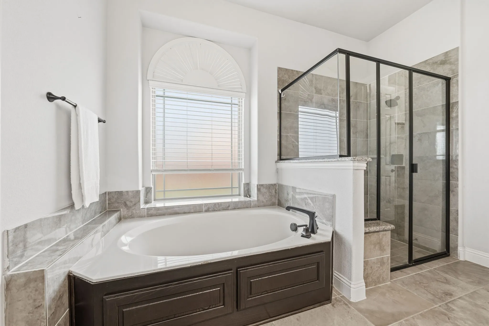 Alcove bathtub with tile surround, paired with a glass-enclosed shower featuring a built-in bench