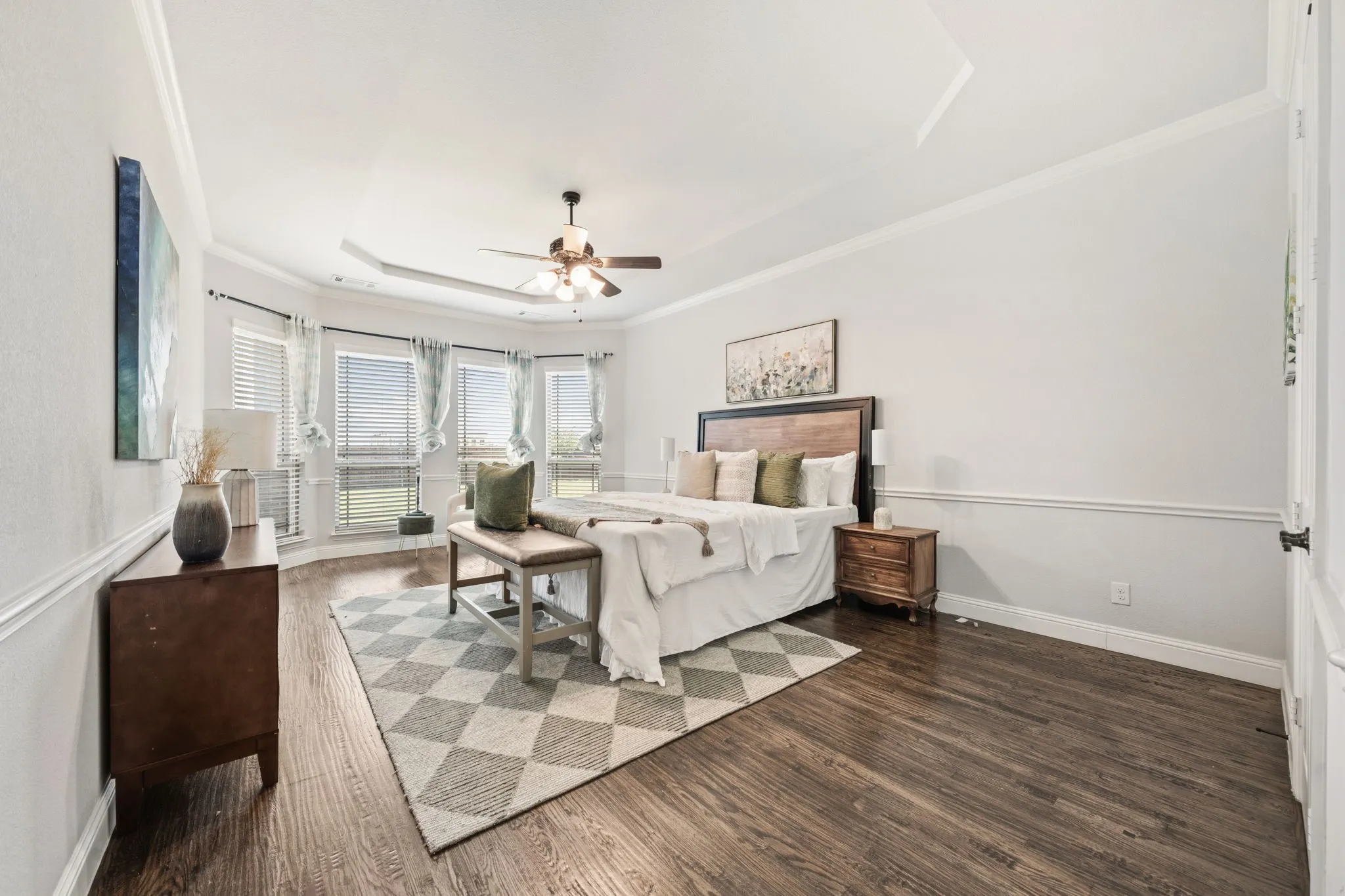 Room featuring wood-finish flooring and a tray ceiling with a ceiling fan