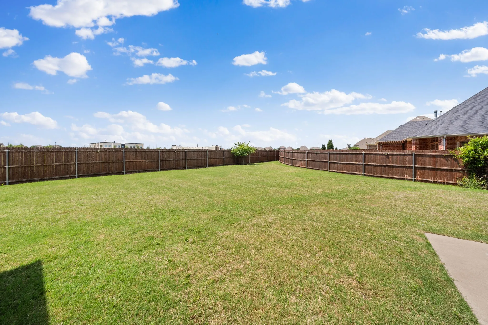 Expansive backyard featuring a manicured lawn and a full privacy fence