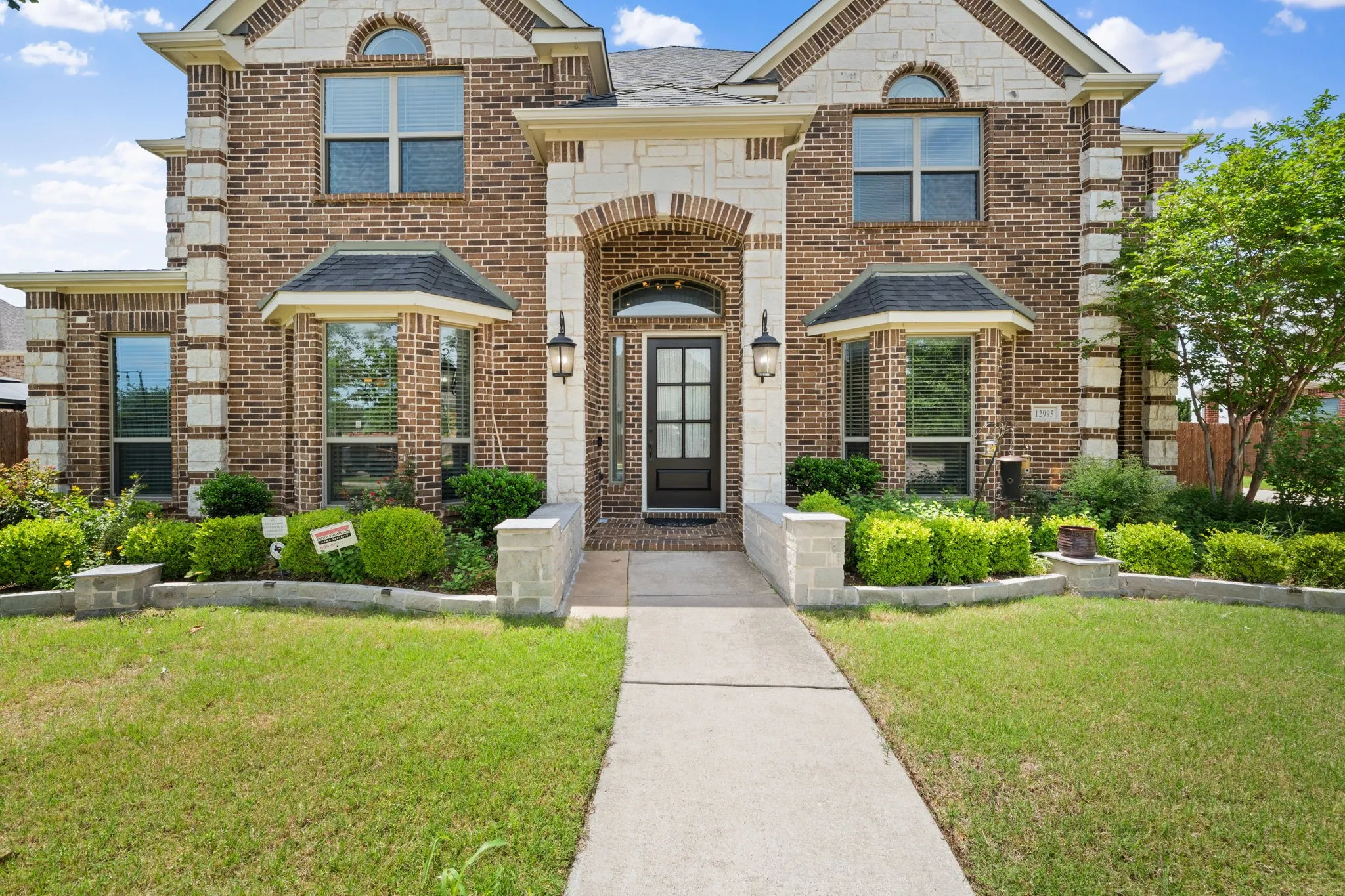 Two-story brick and stone facade featuring architectural bay windows