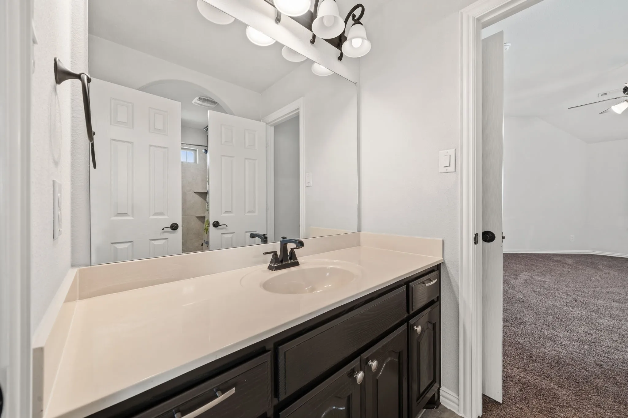 Bathroom vanity with a light-toned countertop, integrated sink, and dark wood-finish cabinetry