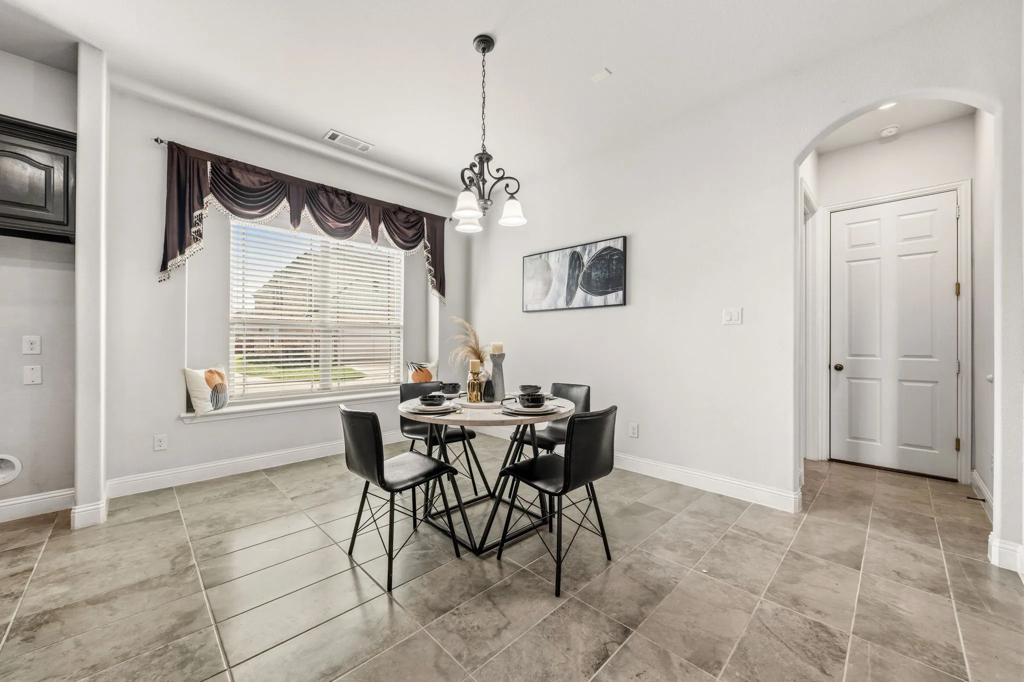 Dining area featuring ceramic tile flooring, a large window with horizontal blinds, and a decorative chandelier