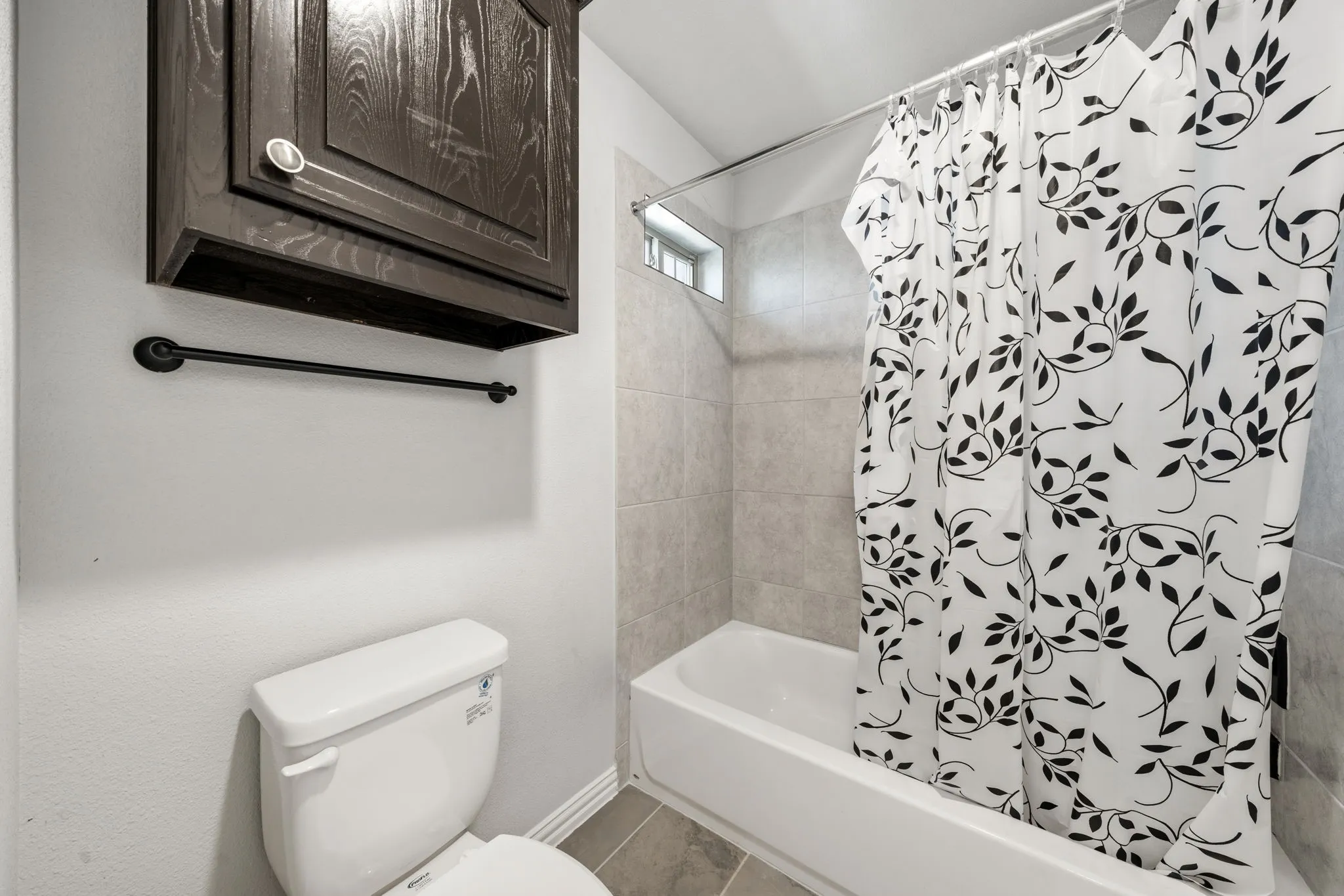 Bathroom featuring a white tub and shower combination with light-toned wall tile