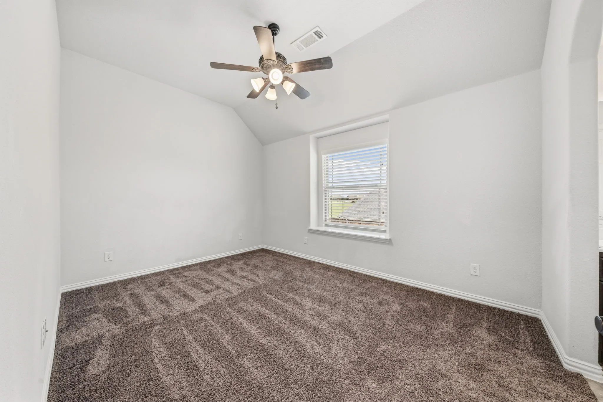 Carpeted room featuring a sloped ceiling, single window with blinds, and a ceiling fan with integrated lighting