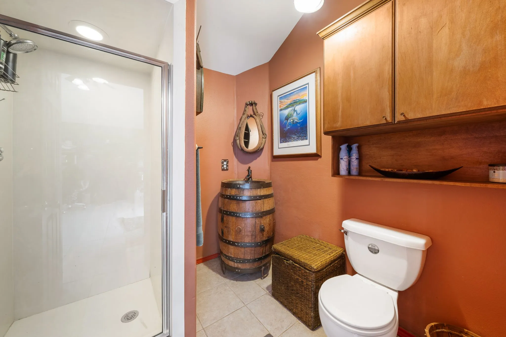 Bathroom featuring a stand-up shower with a glass enclosure, tiled flooring, wood cabinetry with open shelving, a toilet, and a barrel-style vanity