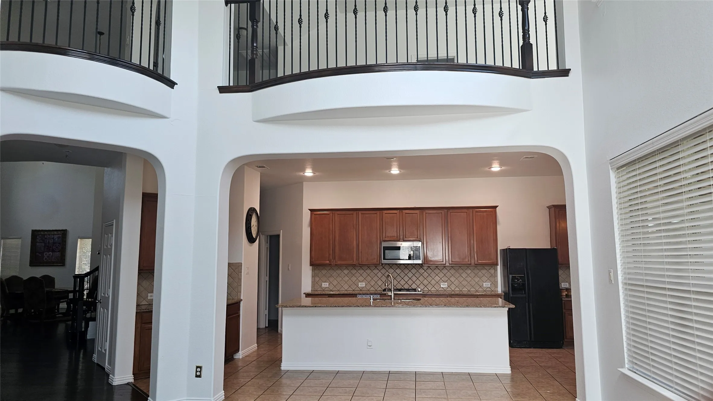 Two-story entryway featuring arched doorways and an open-concept kitchen