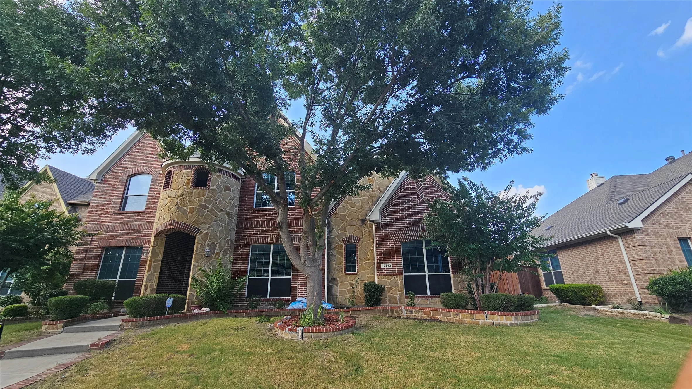 Two-story brick and stone exterior featuring an arched entryway within a stone turret
