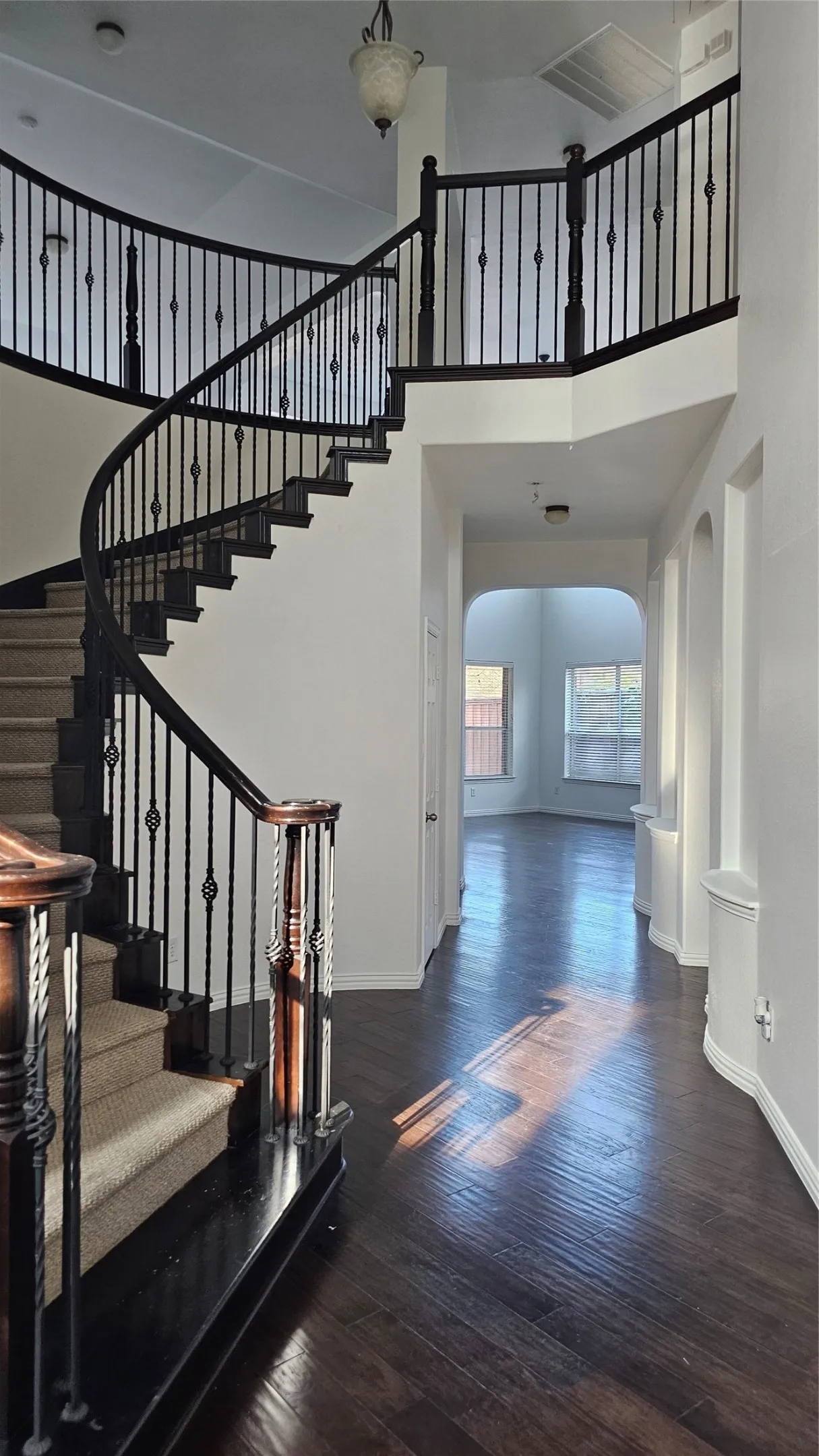 Curved staircase with dark wood-finish handrails and wrought iron balusters