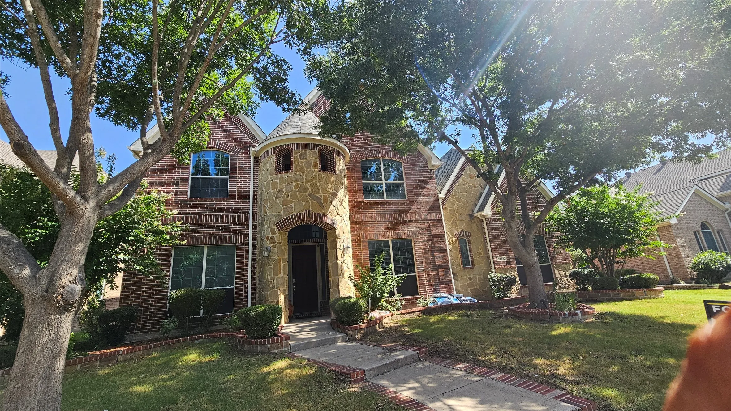 Brick and stone facade residence featuring a prominent rounded turret entrance