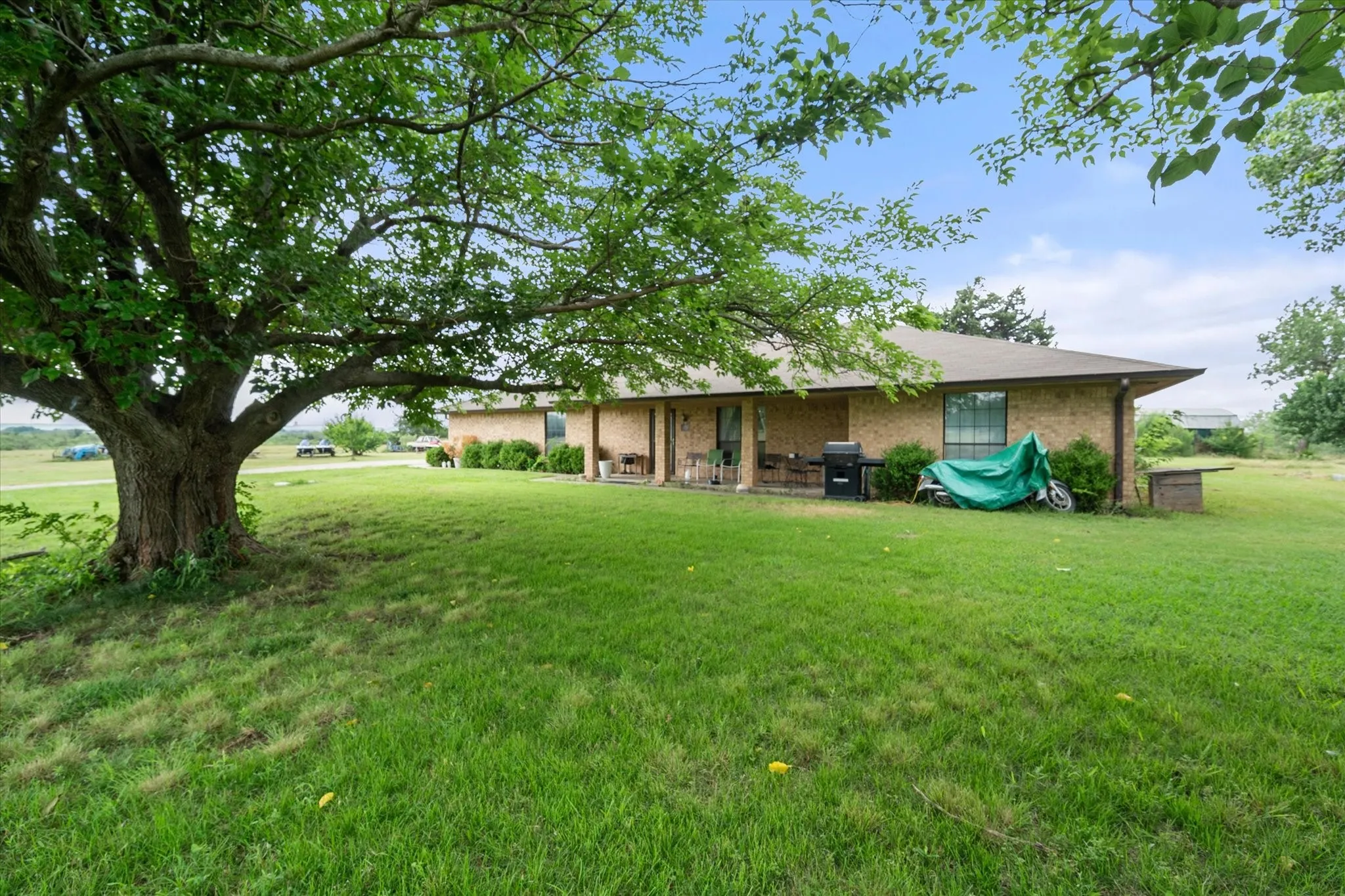 Mature trees and covered front porch make country life near the city still possible.