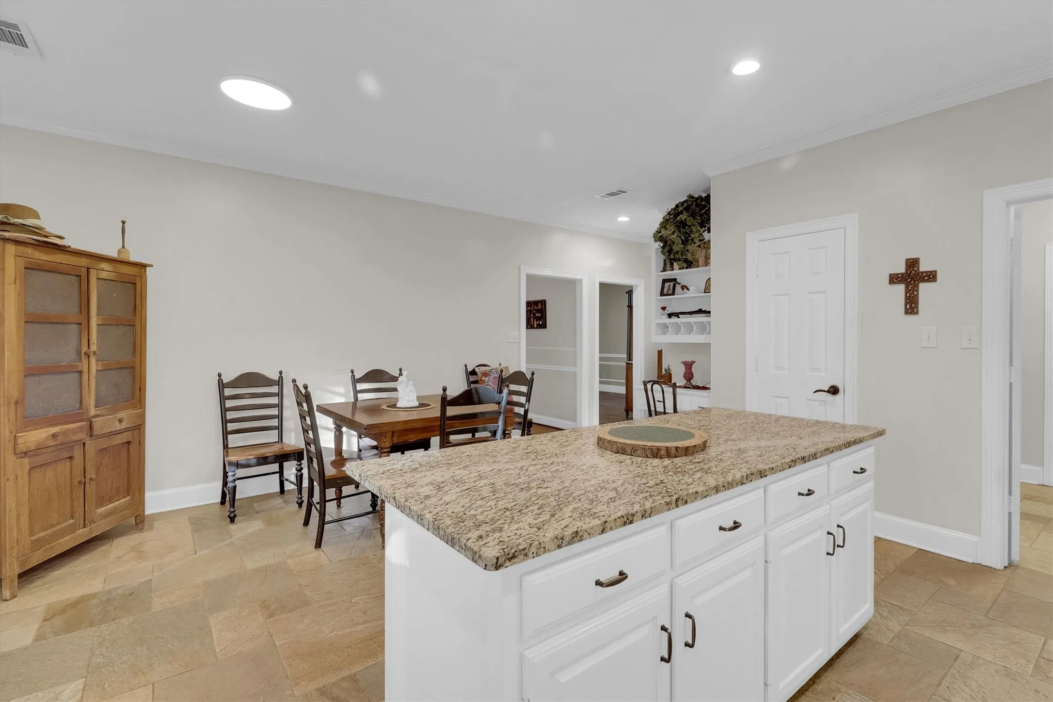 Kitchen featuring a center island, crown molding, recessed lighting, white cabinets, and light stone countertops
