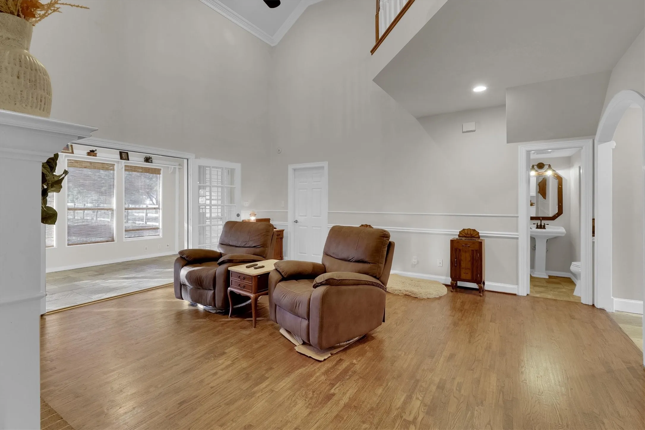 Sitting room with high vaulted ceiling, light wood finished floors, crown molding, and recessed lighting