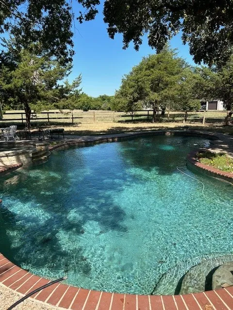 View of swimming pool featuring a fenced backyard and a pool with connected hot tub