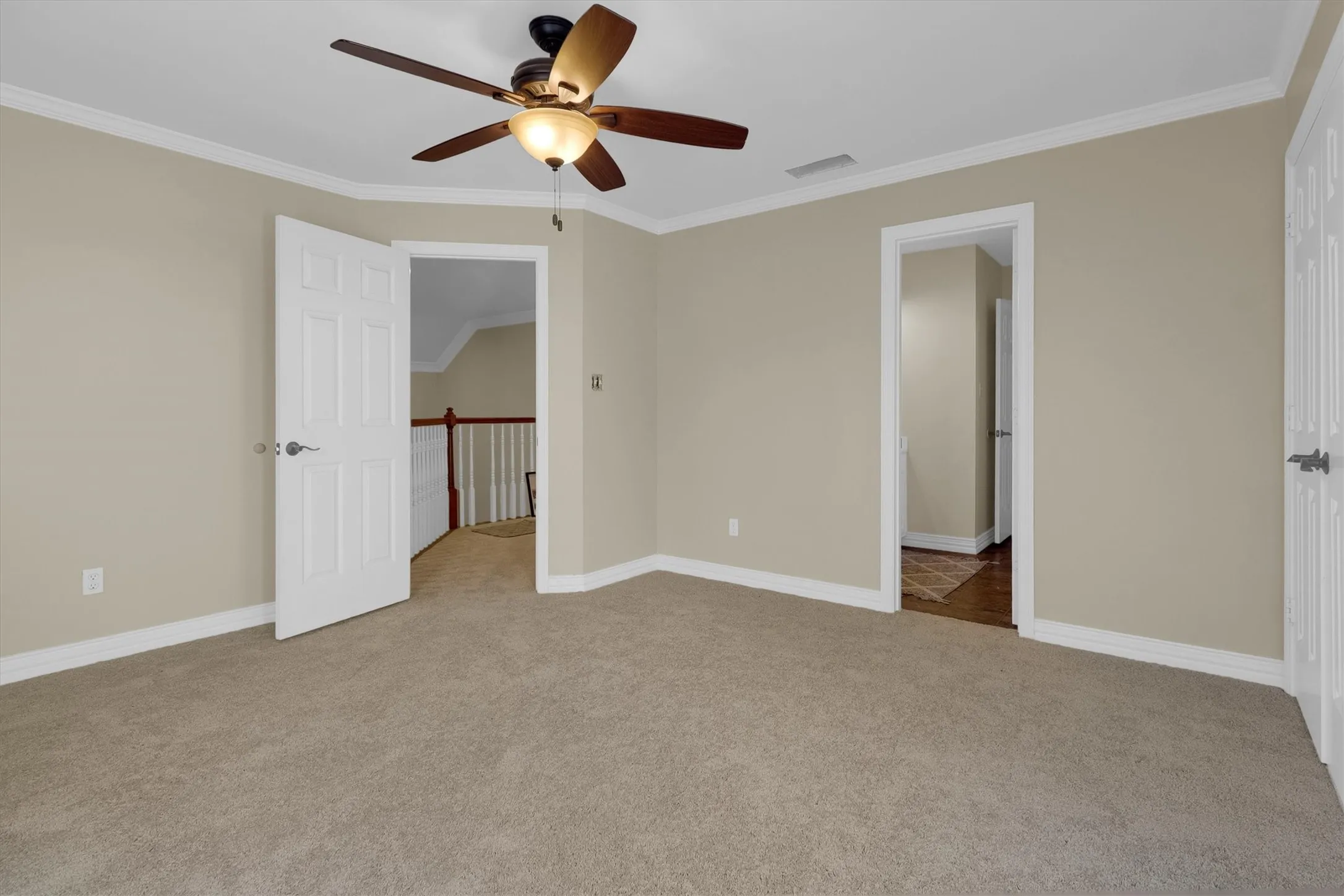 Unfurnished bedroom featuring ornamental molding, light colored carpet, and a ceiling fan
