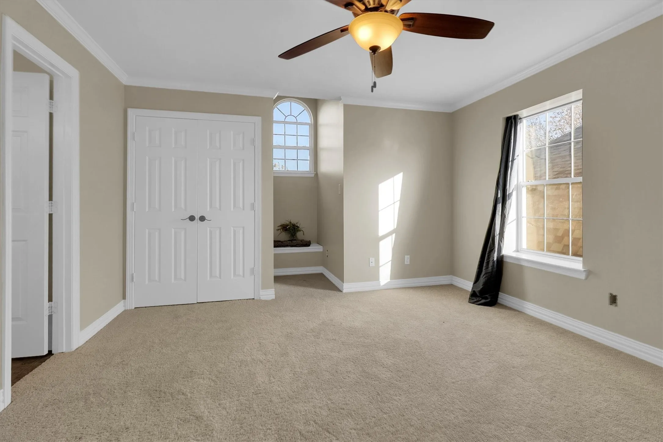Unfurnished bedroom with light colored carpet, crown molding, ceiling fan, and a closet