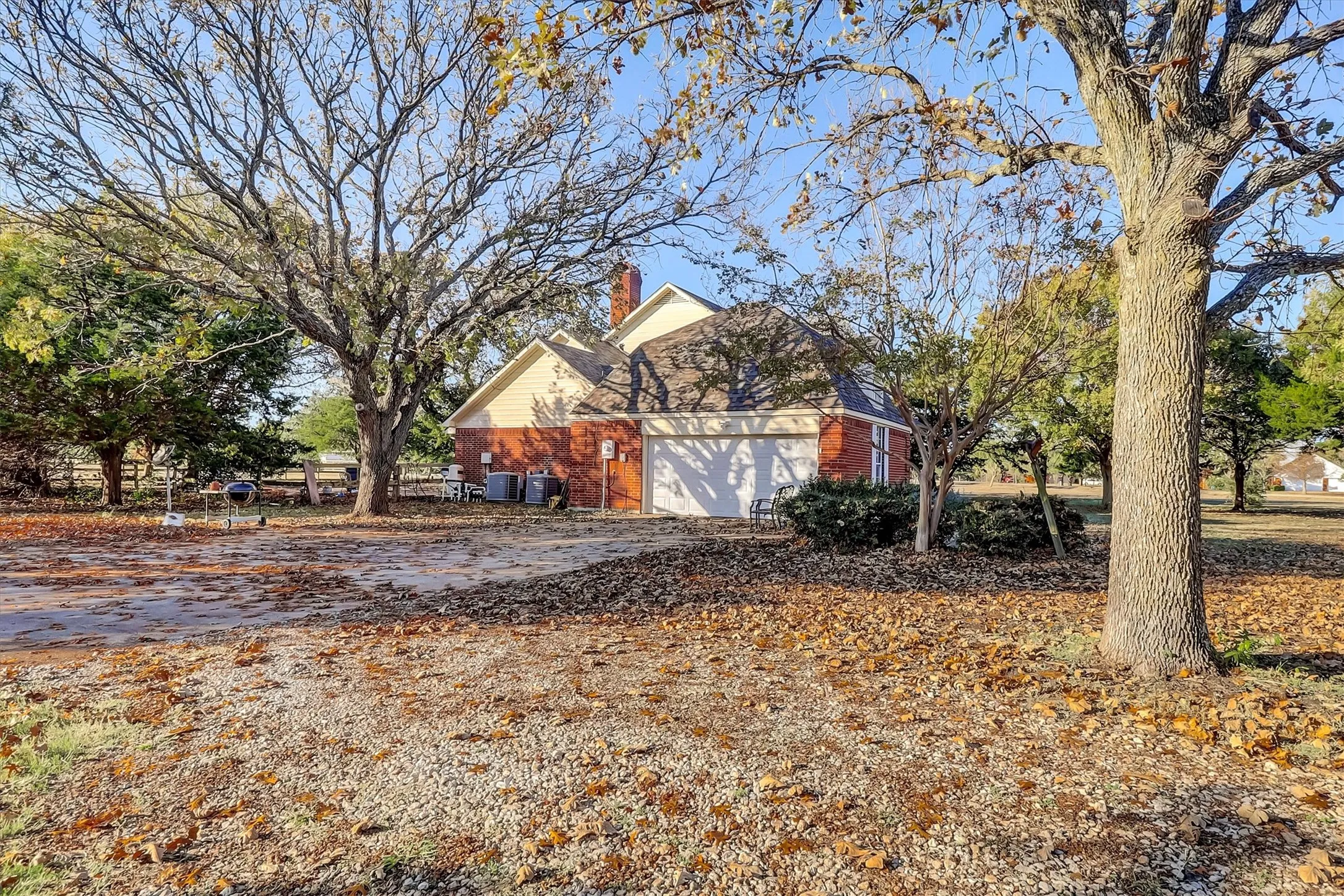 View of property exterior with a chimney, driveway, brick siding, and an attached garage