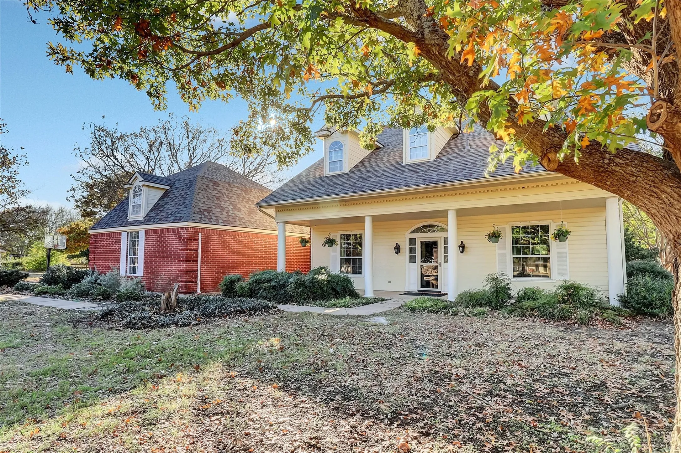 View of front facade featuring covered porch, brick siding, and a shingled roof