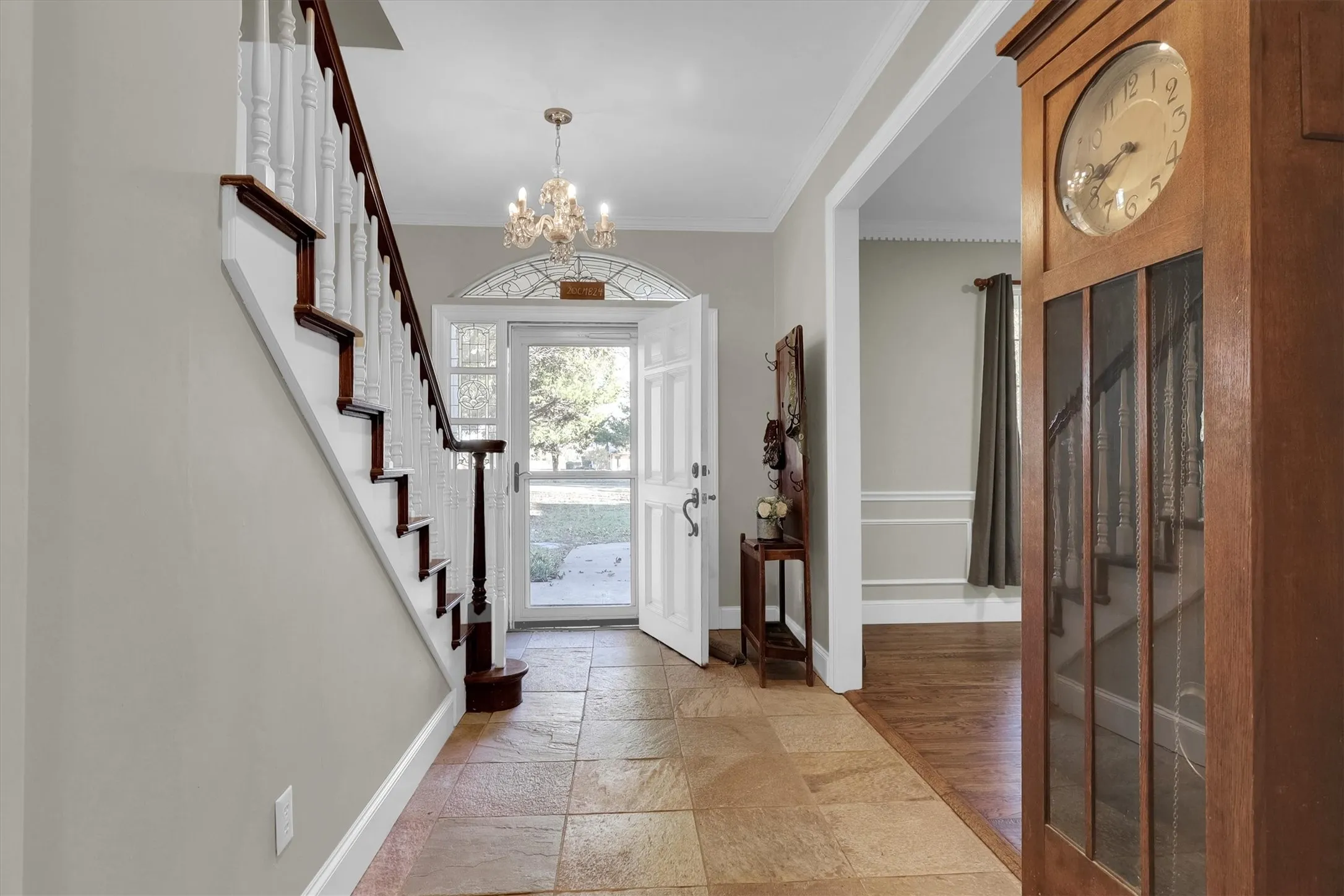 Entryway featuring stone tile floors, ornamental molding, a chandelier, and stairway