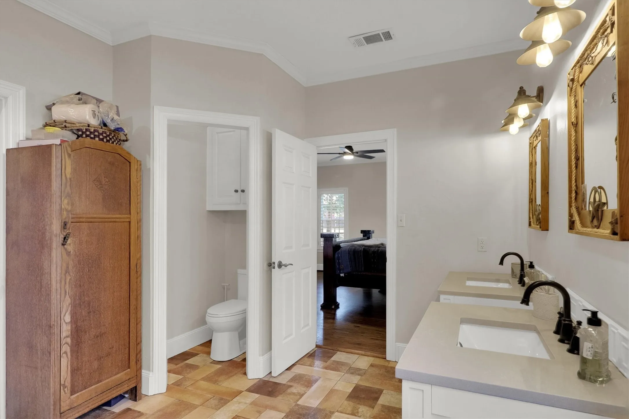 Bathroom with connected bathroom, crown molding, double vanity, and stone finish flooring