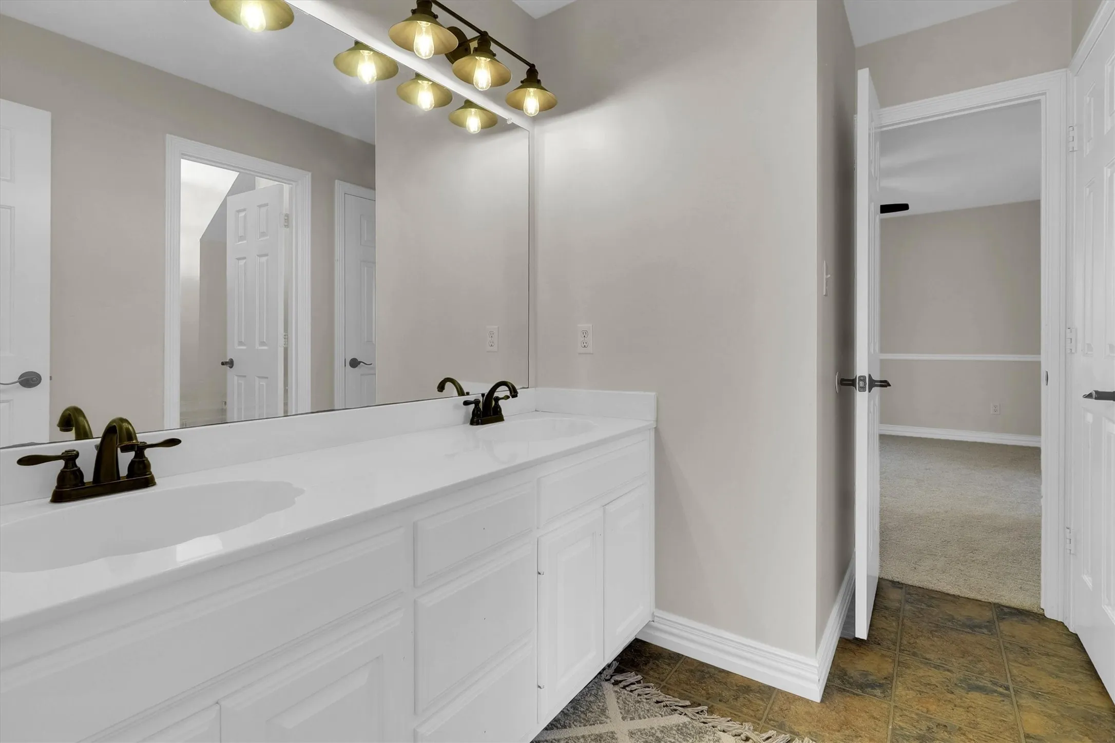 Bathroom with double vanity and dark colored carpet