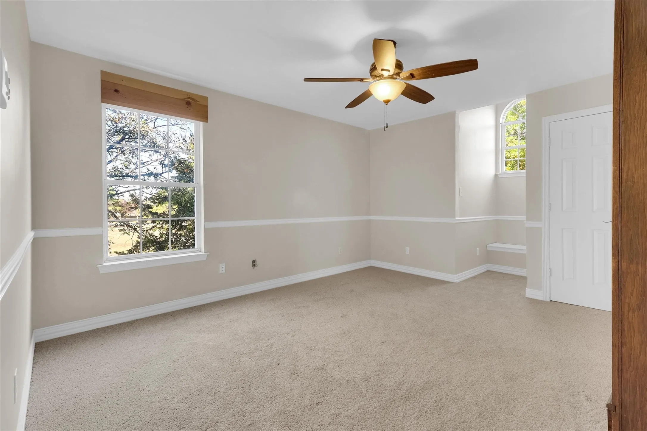 Empty room featuring light colored carpet and a ceiling fan