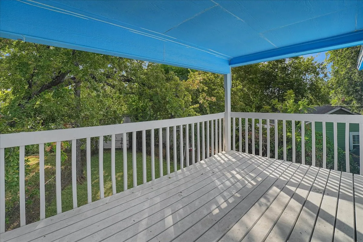 Covered outdoor deck with white painted wood railing and wood plank flooring