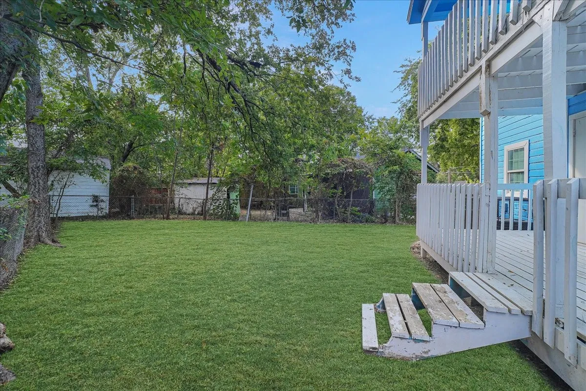 Expansive green lawn, multi-level wooden deck, and a wooden privacy fence