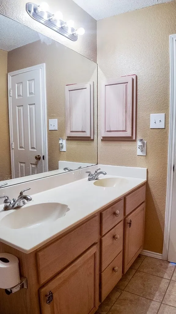 Double vanity with integrated sinks, neutral countertop, and wood-finish cabinetry
