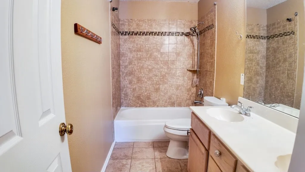 Bathroom featuring a white bathtub, ceramic tile flooring, and a vanity with an integrated sink and wood-finish cabinetry