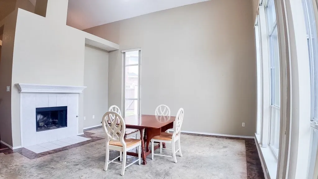 Spacious interior featuring a white tile fireplace with a classic mantel, vaulted ceilings, and large windows with white trim