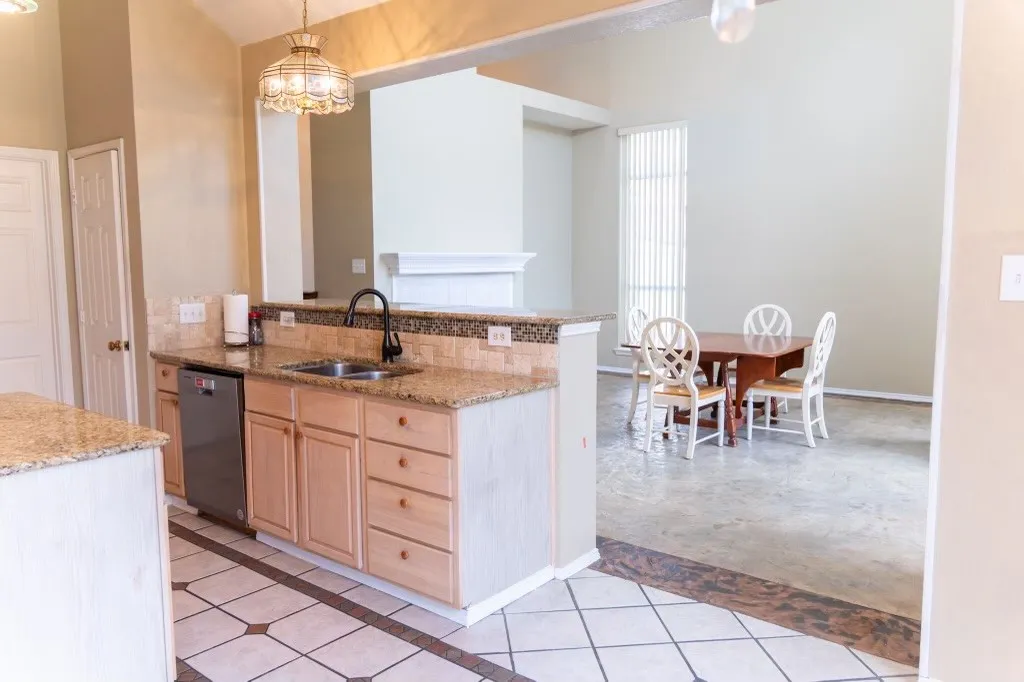 Kitchen featuring granite countertops, a double basin sink with a matte black faucet, and natural wood cabinetry