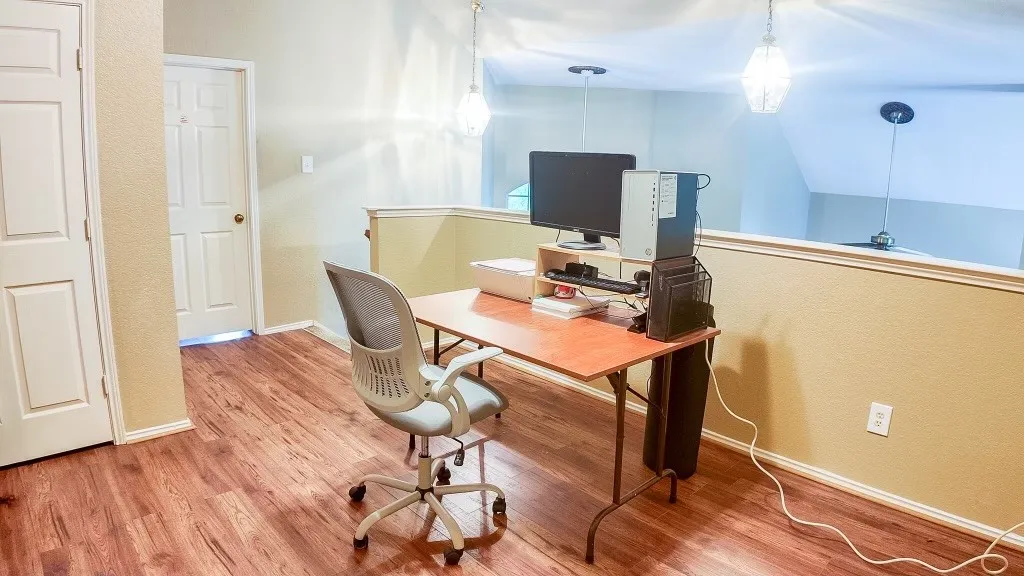 Loft area featuring wood-finish flooring, two pendant light fixtures, and a half-wall partition