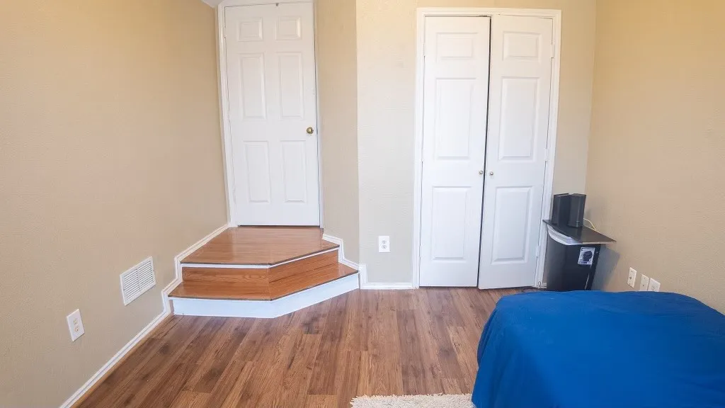 Wood-finish flooring throughout, featuring a multi-level transition to a white paneled door