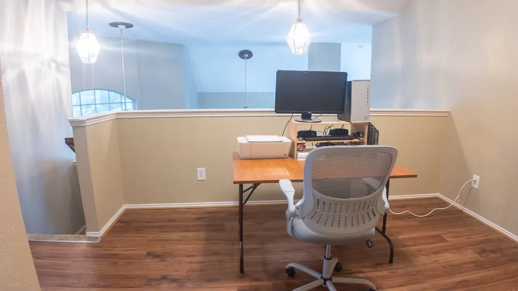 Versatile open-concept area featuring wood-finish flooring, a neutral color palette, and a half-wall partition