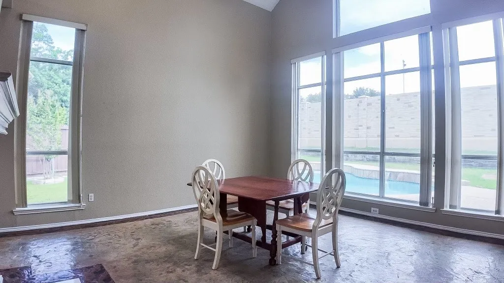 Spacious room featuring a wall of floor-to-ceiling windows, high ceilings, and textured flooring