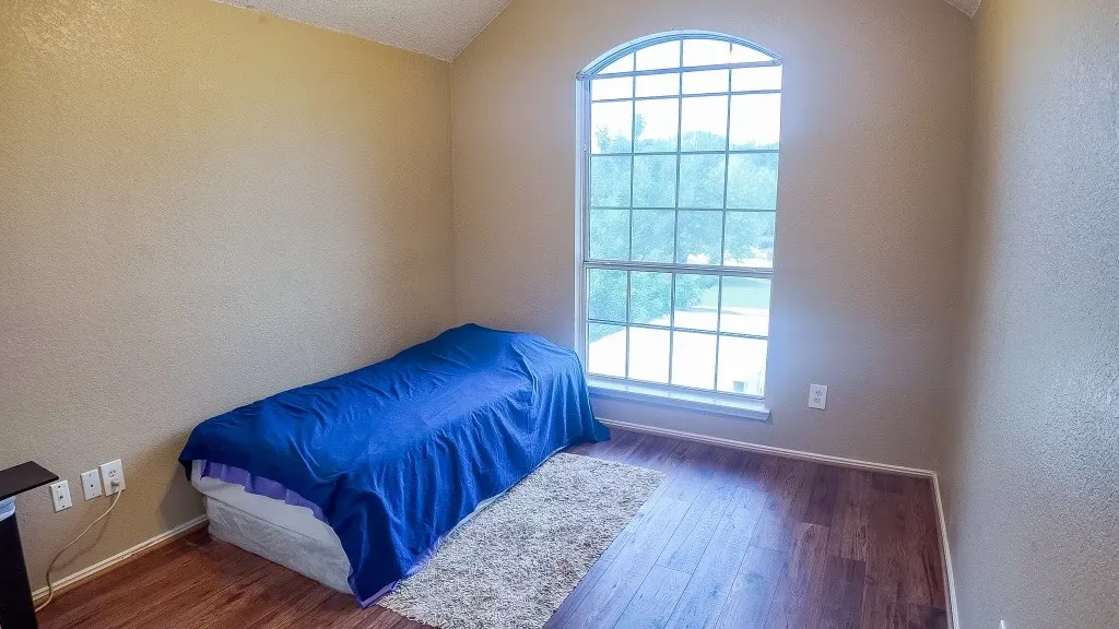 Arch-top window with grid pattern, wood-finish flooring, and neutral wall tones