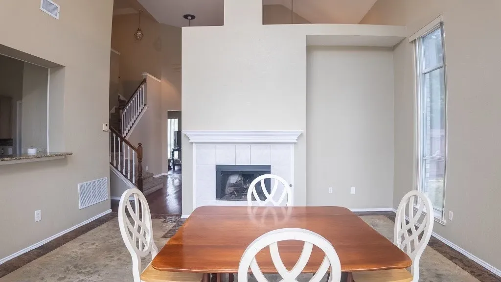 Living space featuring a tile-surround fireplace with a white mantel, high ceilings, an upper architectural cutout, and a tall window