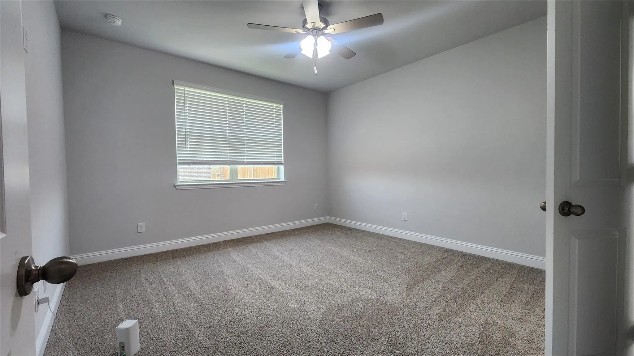 Spacious room featuring neutral carpeting, light gray wall paint, and white trim